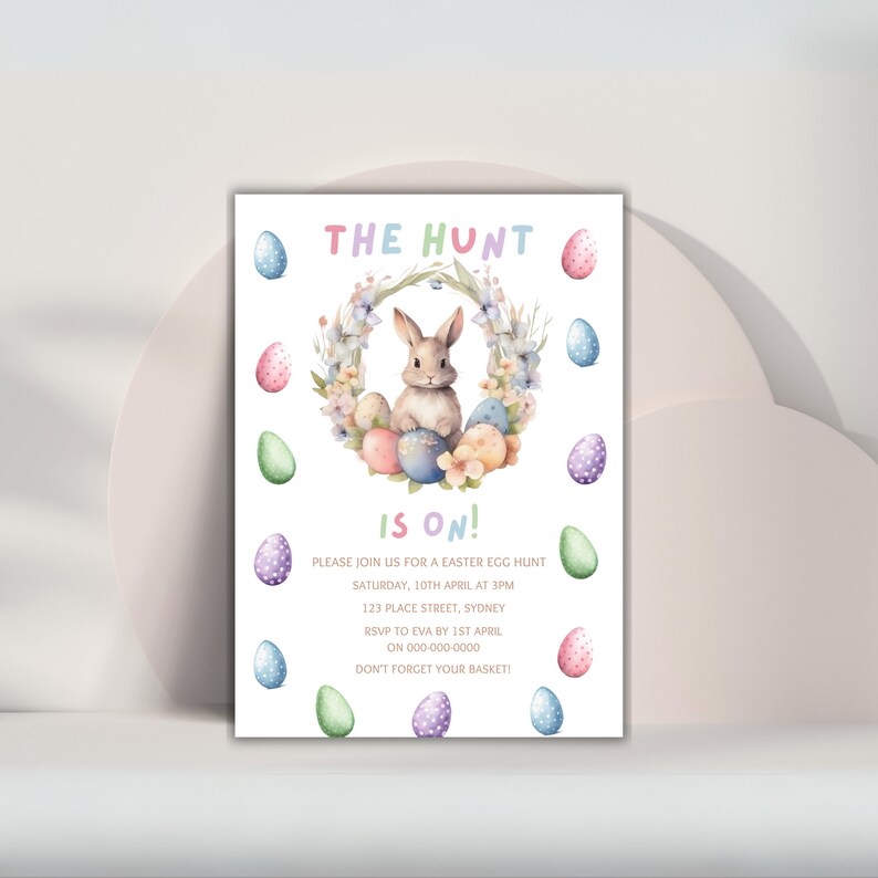 May include: An Easter egg hunt invitation with a watercolor illustration of a bunny rabbit sitting in a wreath of flowers and colorful eggs. The text reads "The Hunt is On!" with details about the event, including the date, time, location, and RSVP information.