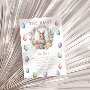 May include: An invitation to an Easter egg hunt with a watercolor illustration of a bunny rabbit sitting in a wreath of flowers and colorful eggs. The text reads "The Hunt is On!" and includes details about the event, including the date, time, location, and RSVP information.