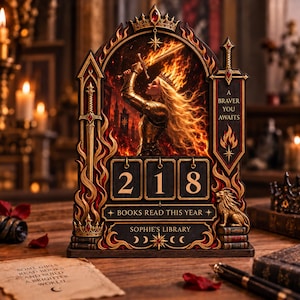 Op de afbeelding: Een decoratieve houten boeken-tracker met een fantasy-illustratie van een krijger met een vlammend zwaard. Het frame bevat een kroon, zwaarden en een leeuw. Het toont het getal 218, de tekst A BRAVER YOU AWAITS, BOOKS READ THIS YEAR en SOPHIE'S LIBRARY.