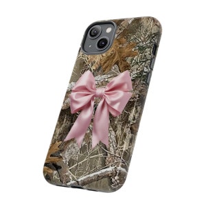 Pode incluir: Uma capa de telefone camuflada com um la&ccedil;o rosa. A capa &eacute; projetada para um iPhone.