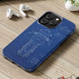 May include: Blue phone case with a motorcycle blueprint design. The case has a dark blue border and a white outline of a motorcycle. The design includes technical drawings and schematics, giving it a vintage, technical aesthetic.