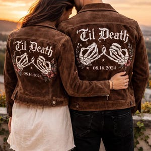 Puede incluir: Dos chaquetas de ante marrón con un gráfico en la espalda de dos manos de esqueleto con los dedos entrelazados, rosas rojas y el texto blanco 'Til Death' sobre la fecha '08.16.2024'. Las chaquetas tienen cuello y puños abotonados.