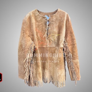 Könnte beinhalten: Hellbraune Wildlederjacke mit Fransen an Ärmeln und Saum. Die Jacke hat eine Schnürung vorne und einen runden Ausschnitt. Das Logo von Hummingbird Leather Wears ist sichtbar. Mittlere Größe.