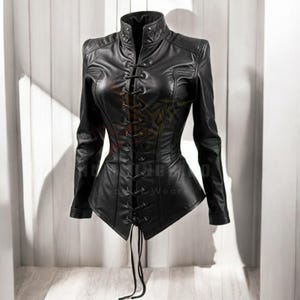 Pode incluir: Uma jaqueta de couro preta com fecho de renda na frente e uma silhueta ajustada. A jaqueta tem um colarinho alto e mangas compridas.