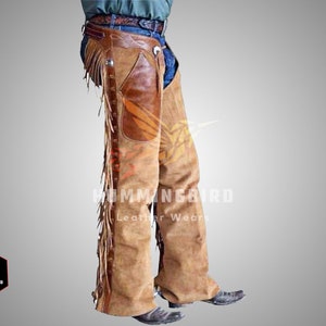 Könnte beinhalten: Ein Paar braune Lederchaps mit Fransen und einem braunen Lederflicken am rechten Bein. Die Chaps werden über einer blauen Jeans und einem braunen Gürtel getragen.