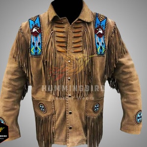 May include: A brown suede jacket with fringe detailing and Native American inspired beadwork. The jacket features a beaded eagle design on the shoulders and a circular design on the chest and sleeves. The jacket has a button-up front and long sleeves.