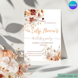 Könnte beinhalten: Eine weiße Einladungskarte mit dem Text "Lily Moore's birthday party" in eleganter Schrift. Die Karte ist mit floralen Arrangements in Braun-, Orange- und Cremetönen verziert. Die Veranstaltungsdetails sind ebenfalls enthalten.