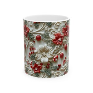 K&ouml;nnte beinhalten: Wei&szlig;er Keramikbecher mit einem gepr&auml;gten Design aus roten Weihnachtssternen, Zuckerstangen und Beeren. Das Design umfasst eine gro&szlig;e wei&szlig;e Blume und gr&uuml;ne Bl&auml;tter, die ein festliches Urlaubsthema schaffen. Der Becher ist zylindrisch mit wei&szlig;em Innenraum.
