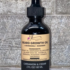 May include: A dark brown glass bottle with a black dropper top and a label that reads "Beard Growth Oil w/Bhringraj. Rosemary" and lists the ingredients. The label also includes the text "Iman Yvonne Beauty" and "Cardamom & Cedar 2 fl oz/ 60 ml".
