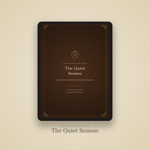Könnte beinhalten: Ein digitales Tablet mit einem dunkelbraunen Journal-Cover mit dem Titel The Quiet Season. Das Cover zeigt goldenen Text, ein zentrales kreisförmiges Emblem und dekorative Verzierungen an den Ecken. Der Text lautet A Seasonal Reflection Journal, The Quiet Season, autumn & winter notes for slowing down and turning inward und The Gentle Observer.
