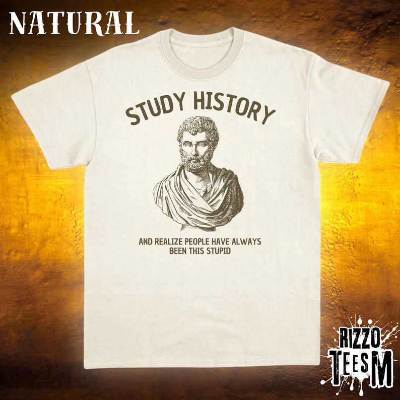 May include: A cream-coloured t-shirt featuring the words "STUDY HISTORY" above a bust illustration. Underneath, the text reads "AND REALIZE PEOPLE HAVE ALWAYS BEEN THIS STUPID." The shirt has a crew neck and short sleeves.