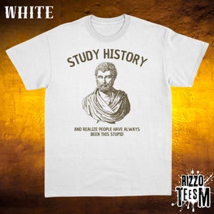 May include: White t-shirt featuring the words "STUDY HISTORY" above a sepia-toned bust. Beneath the bust, the text reads "AND REALIZE PEOPLE HAVE ALWAYS BEEN THIS STUPID." The shirt has a crew neck and short sleeves.