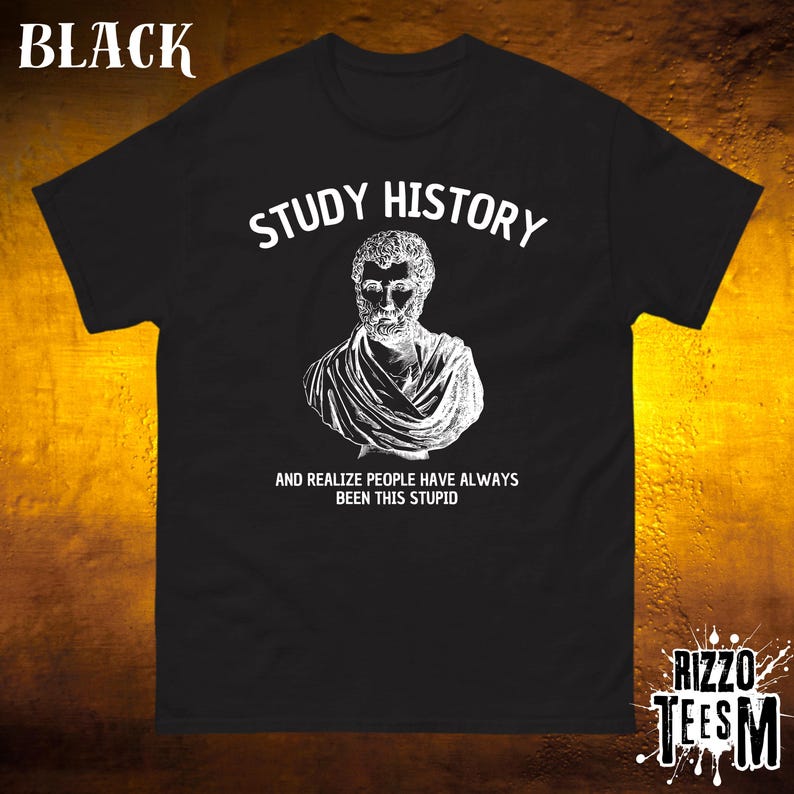 May include: Black t-shirt featuring the text "STUDY HISTORY" and a white bust illustration. Underneath, the text reads "AND REALIZE PEOPLE HAVE ALWAYS BEEN THIS STUPID." The shirt has a crew neck and short sleeves.