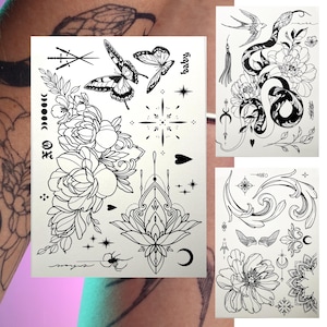 Puede incluir: Tres hojas de tatuajes temporales con diseños de tinta negra. La primera hoja presenta un diseño floral con mariposas, estrellas y una luna creciente. La segunda hoja presenta una serpiente envuelta alrededor de una flor con un pájaro volando por encima. La tercera hoja presenta un diseño floral con una luna creciente, una cruz y un diseño estilizado.