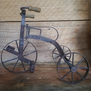 A vintage (9.5  in. tall)  mini tricycle-  a metal doll tricycle- missing the wooden seat- great for primitive or rustic decor or photo shot