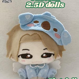 May include: A plush flat doll with light brown hair, wearing a light blue sleep mask with brown and pink details, and a light blue onesie with white star patterns. The doll has embroidered facial features, pink cheeks, and small white wings on the back. Text reads Custom 2.5D dolls and Flat doll.