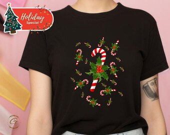 May include: Black t-shirt featuring a festive Christmas design. The shirt is adorned with candy canes, holly leaves, and red berries. A red and white banner with the words "Holiday Special" is in the upper left corner.