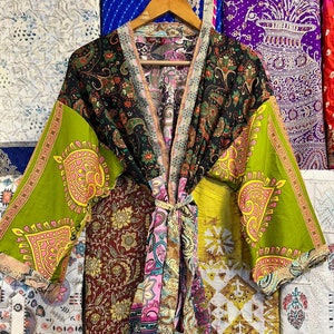 Puede incluir: Una bata kimono de patchwork colorida con un estampado floral negro, verde y rosa. La bata tiene un cinturón de atar y mangas largas.