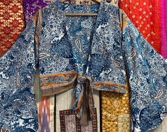 May include: A blue and white paisley patterned kimono with orange trim and a tie closure. The kimono has long sleeves and a relaxed fit.
