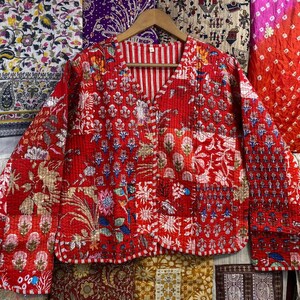 May include: A red quilted jacket with a floral print and gold accents. The jacket has a V-neck and a button closure.