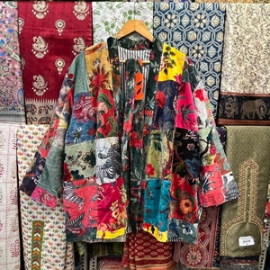 Op de afbeelding: Een kleurrijk patchworkjack met verschillende bloemen- en dierenprints. Het jack is gemaakt van verschillende stoffen en texturen, waaronder fluweel en katoen. Het jack heeft lange mouwen en een losse pasvorm.