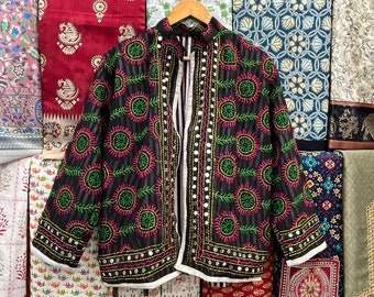 May include: A black embroidered jacket with green and pink floral designs and silver mirror embellishments. The jacket has a white trim and a button closure.