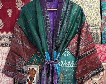 May include: A colorful silk robe with a patchwork design. The robe is made of different fabrics and colors, including green, purple, blue, and red. The robe is tied at the waist with a purple sash.