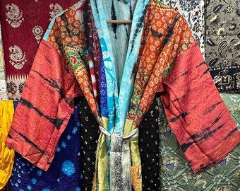 May include: A colorful patchwork kimono robe with a tie belt. The robe is made of different fabrics with various patterns and colors, including red, blue, green, yellow, and orange.