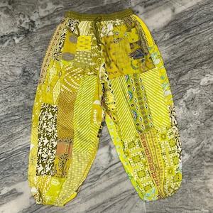 Peut inclure: Pantalon jaune et vert en patchwork avec une taille à cordon. Le pantalon est fait de différents tissus et a un style bohème.
