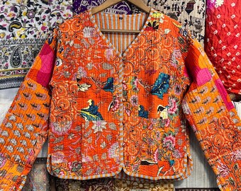Puede incluir: Una chaqueta acolchada de color naranja brillante con un estampado floral y cuello en V. La chaqueta está hecha de tela de patchwork y tiene un cierre de botón.