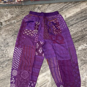 Peut inclure: Pantalon en patchwork violet avec une taille élastique et un cordon de serrage. Le pantalon est fait d'un tissu doux et confortable et a une coupe décontractée.