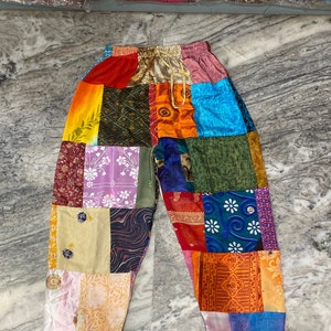 Peut inclure: Pantalon patchwork fait de chutes de tissus colorés. Le pantalon a une taille à cordon et une coupe ample.