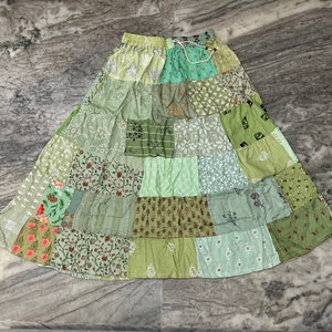 Puede incluir: Una falda de patchwork hecha de diferentes telas verdes con estampados florales. La falda tiene una cintura elástica y una silueta fluida.