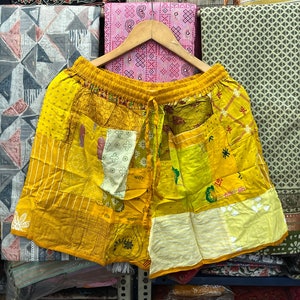 Peut inclure: Short en patchwork jaune avec une taille à cordon. Le short est fait de différents tissus, dont du coton et de la soie. Le tissu est un mélange de jaune, de blanc et de marron.