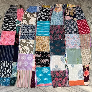 Puede incluir: Un pantalón de pierna ancha con un diseño de patchwork compuesto por varios paneles de tela rectangulares. La prenda muestra una diversa gama de colores que incluye rosa, azul, negro, blanco, verde y marrón, con variados estampados florales y geométricos.