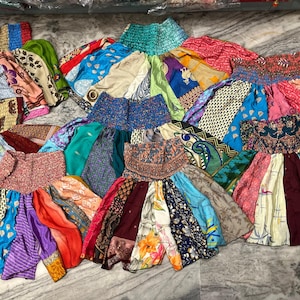 Könnte beinhalten: Eine Sammlung bunter Patchworkröcke aus recycelten Saris. Die Röcke sind alle in verschiedenen Größen und Formen und mit einer Vielzahl von Mustern und Farben verziert.