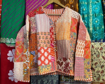 May include: A patchwork quilted jacket with a button closure. The jacket is made of various fabrics in shades of orange, pink, and red. The fabric is patterned with floral designs and stripes.
