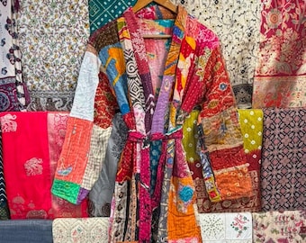May include: A long-sleeved robe featuring a patchwork design made from various colorful fabrics with intricate patterns. The garment includes a matching fabric belt at the waist, a shawl collar, and visible kantha-style stitching throughout.