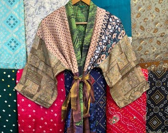 May include: A long-sleeved kimono-style robe featuring a patchwork design with various patterns and colors, including green, tan, and dark blue. The garment has a tie-waist closure and wide sleeves, constructed from multiple fabric panels with distinct prints.