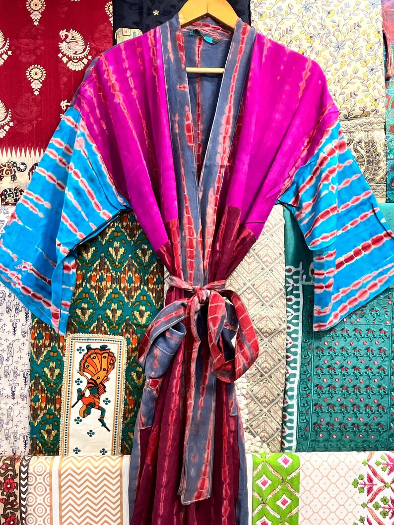 May include: A long, pink, blue, and gray silk robe with a tie belt. The robe has a tie-dye pattern and is made of a soft, flowing fabric.