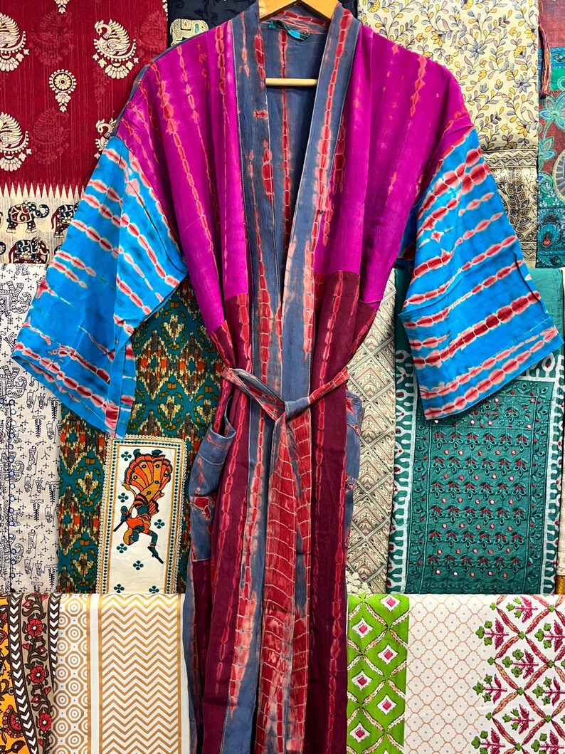 May include: A long, colorful tie-dye robe with a blue and red striped pattern. The robe has a sash tie and a pocket on the left side.
