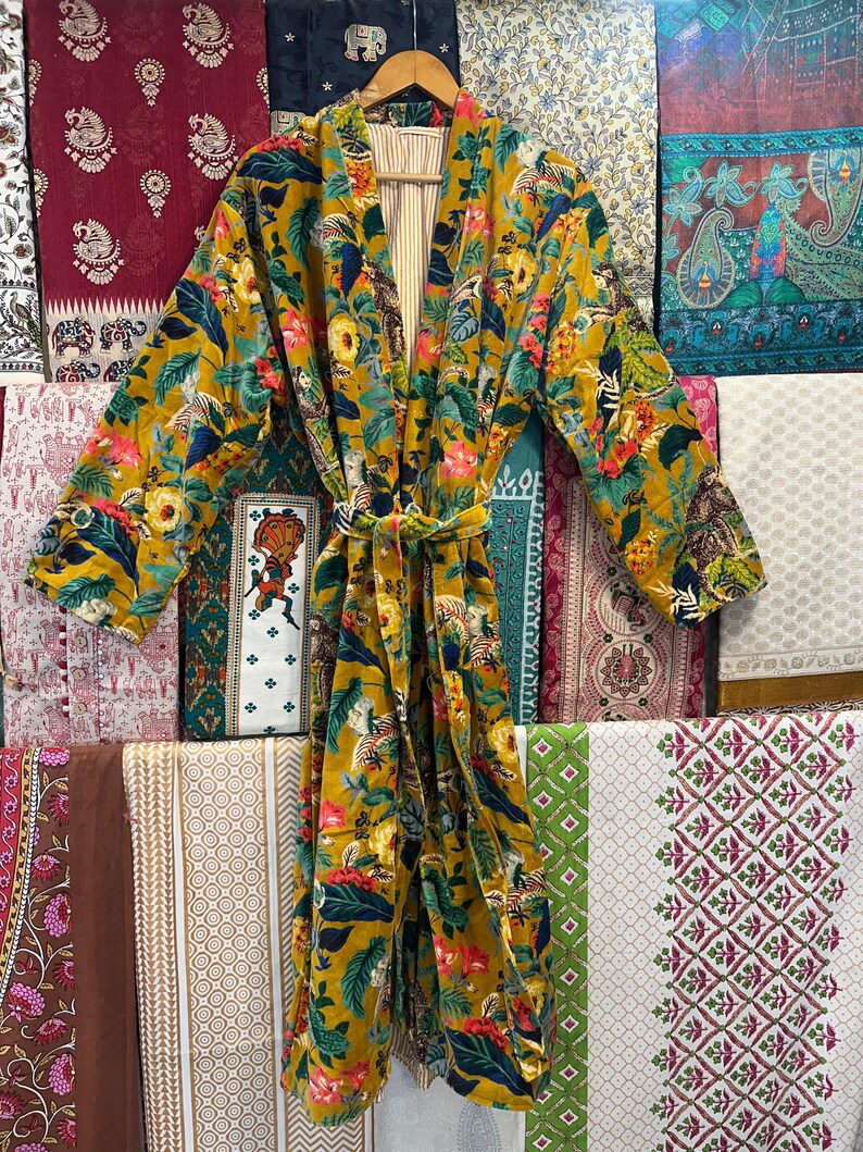 May include: A yellow floral patterned robe with a long sleeve and a tie belt. The robe is made of a soft, velvet-like fabric.