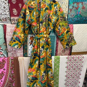 May include: A long, yellow floral robe with a green, blue, and red floral print. The robe has a sash tie at the waist.