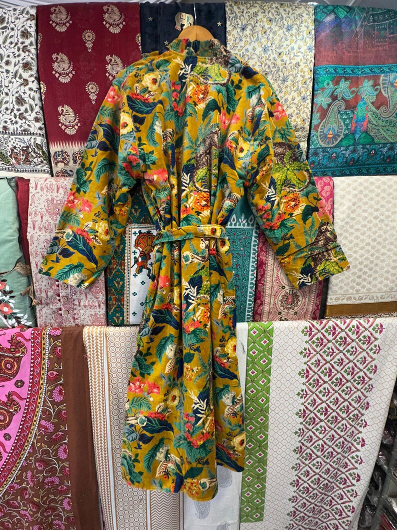 May include: A long, yellow floral robe with a green, blue, and red floral print. The robe has a sash tie at the waist.
