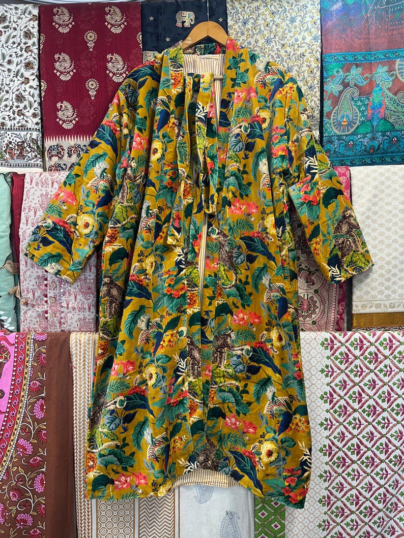 May include: A long, yellow, floral patterned robe with a tie belt. The robe has a green, blue, and red floral pattern with a variety of birds and animals.