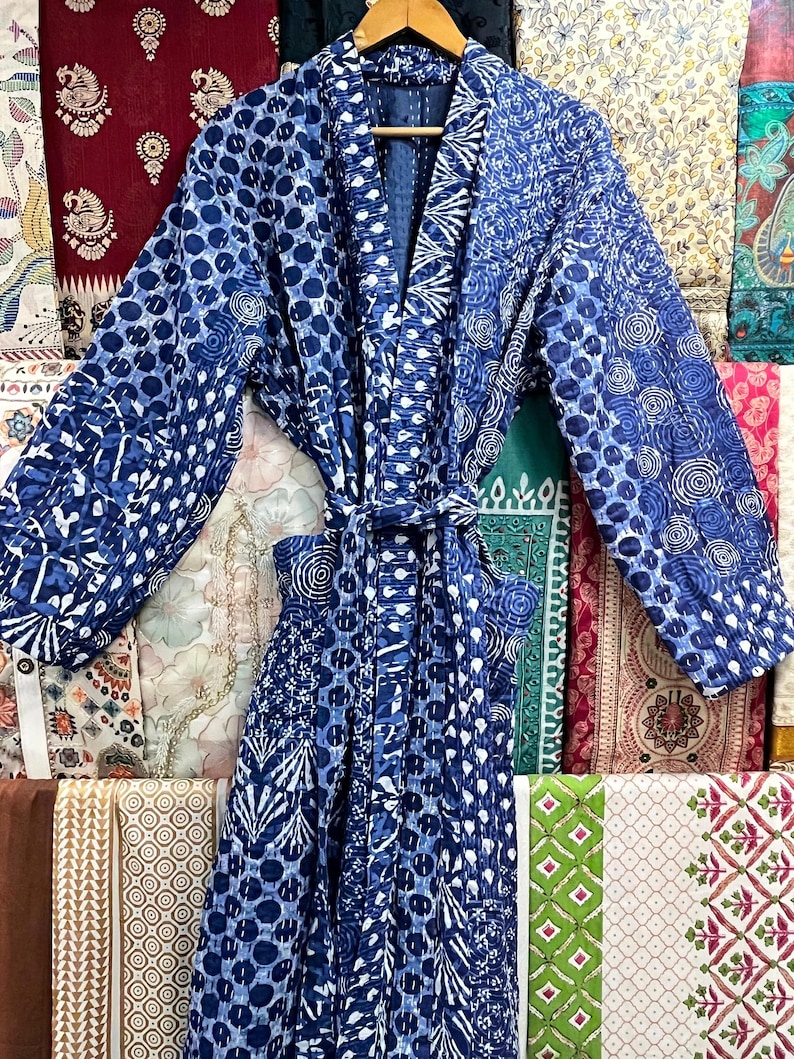 Op de afbeelding: Een blauwe en witte gequilte badjas met een strikceintuur. De badjas heeft een traditionele Japanse stijl met een brede kraag en lange mouwen.