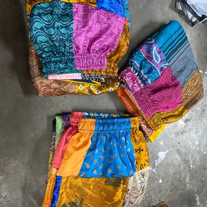 Può includere: Una gonna patchwork colorata realizzata con tessuto riciclato. La gonna presenta una varietà di motivi e colori, tra cui blu, verde, rosa, giallo e marrone. La gonna ha una vita con coulisse ed è perfetta per uno stile bohémien o hippie.