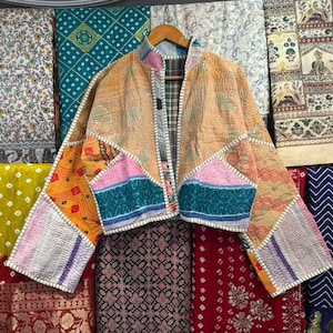 May include: A cropped jacket constructed from quilted fabric patches in various colors including orange, pink, teal, and yellow. The garment features a stand-up collar, long sleeves, and visible white stitching throughout the patchwork design.
