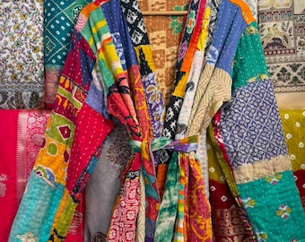 May include: A long-sleeved robe crafted from a patchwork of multicoloured cotton fabrics featuring various floral, geometric, and abstract patterns. The garment includes a matching tie belt and visible white running stitch quilting throughout.