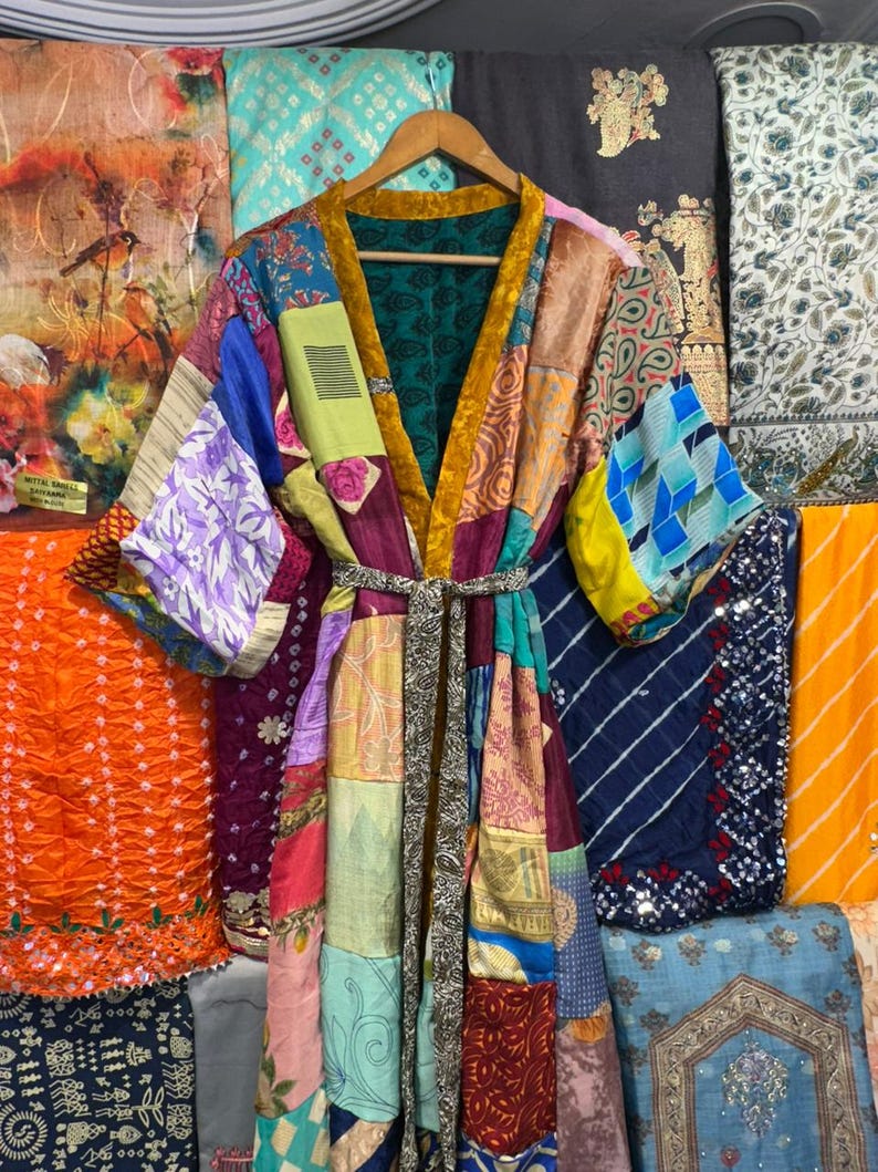 May include: A patchwork kimono robe with a variety of colorful fabric patterns. The robe has a gold trim and a matching belt. The background features various patterned fabrics.